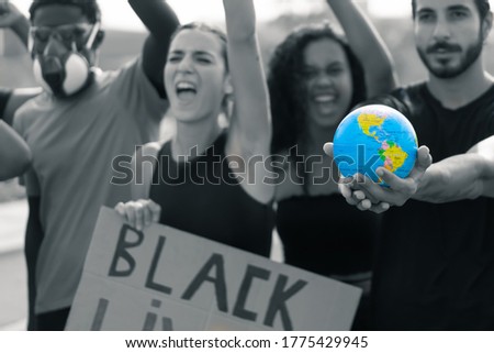 Equality in the world on top of mind. Multiracial group asking for human rights. Young activist holding the world in is hands. Focus on the globe. Image