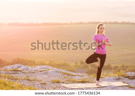 A girl in the background of a beautiful look engaged in yoga at dawn in the mountains.