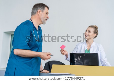 Doctor In Discussion With Nurse At Nurses Station or Hospital Reception