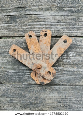 Old metal platinum connected by a rusty bolt against the background of aged boards