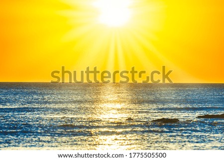 Sunset sea and beach with rocks and sunset sun on dramatic sky