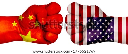 The concept of the struggle of peoples. Two hands are clenched into fists and are located opposite each other. Hands painted in the colors of the flags of the countries. China vs USA