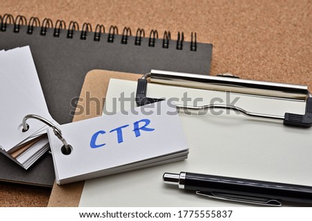 On top of the notebook and clipboard is a wordbook and pen with the word CTR written on it. It means Click Through Rate.