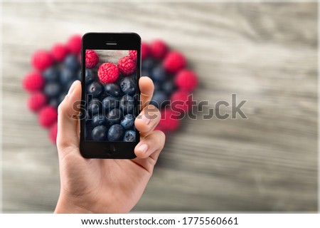 Hands of a woman using an application on a smartphone to take picture of the food
