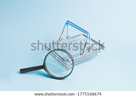 magnifier and small toy shopping basket on a blue background, copy space, shopping concept