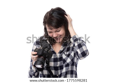 Young female freelance professional photographer or art student or photojournalist on a white background holding a camera. She is confused or shy
