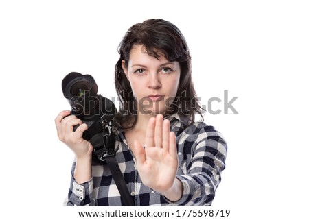 Young female freelance professional photographer or art student or photojournalist on a white background holding a camera telling client to stop