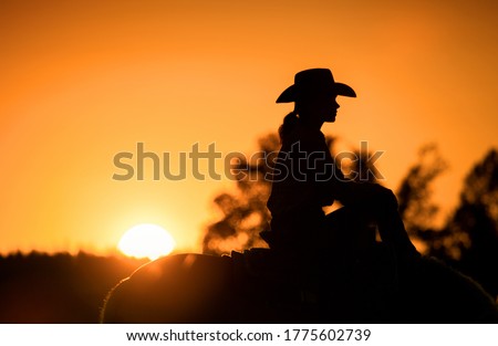Cowgirl with her horse at sunset Royalty-Free Stock Photo #1775602739
