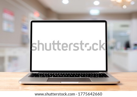 Laptop blank screen on wood table with hospital or clinic background, mockup, template for your text, Clipping paths included for background and device screen