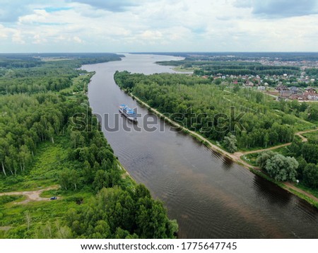 Aerial view river cruise ship sails along the river surrounded by beautiful green forest in summer on a sunny day. Cruise Ship Trip