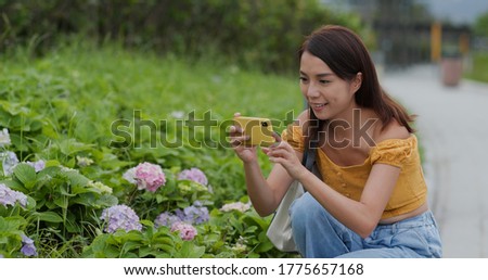 Woman take photo on cellphone in flower field