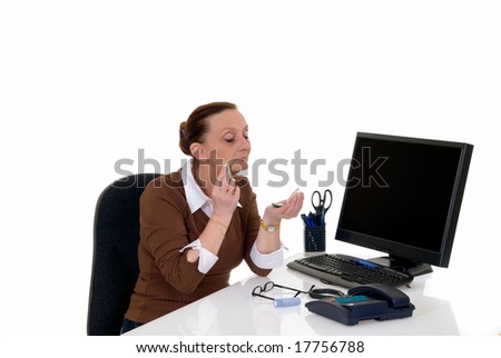 Attractive middle aged businesswoman working in office on computer, putting on make up,  white background,  studio shot.