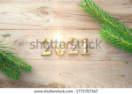 Gold numbers 2021 on a wooden background with Christmas decorations: green branches of spruce, red ball. New Year concept, frame, top view. Copy space. Merry Christmas and Happy New Year symbol's