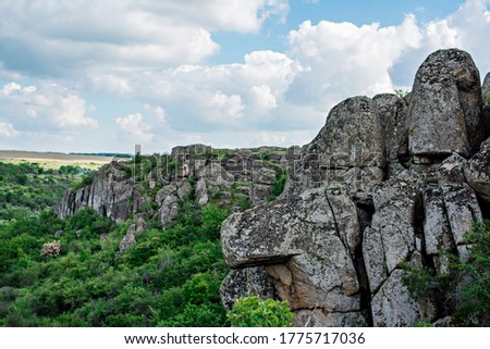 Stone gray canyon among green trees, river between the mountain. One of the Wonders of the World of Ukraine is the Act of Devil's Canyon. Traveling around the country by car, climbing, climbing 