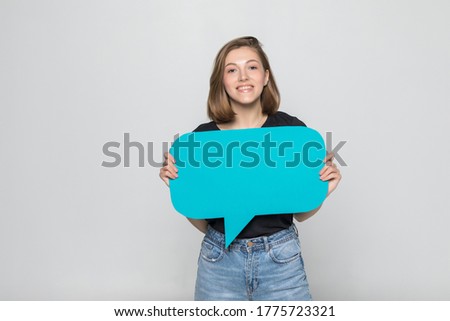 Beautiful woman holding blank speech bubble over grey background