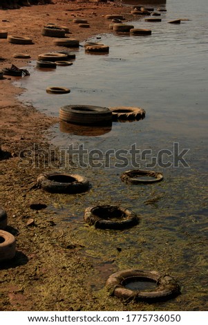 Dirty polluted waterside with old tyres