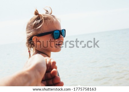 child pulls father to swim in the sea.