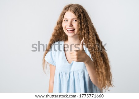 Good job. Pretty carefree modern stylish European girl with curly long hair making gesture OK, as if saying that everything is finee, white background.