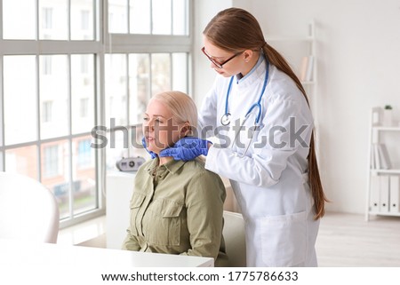 Doctor examining senior woman with thyroid gland problem in clinic Royalty-Free Stock Photo #1775786633