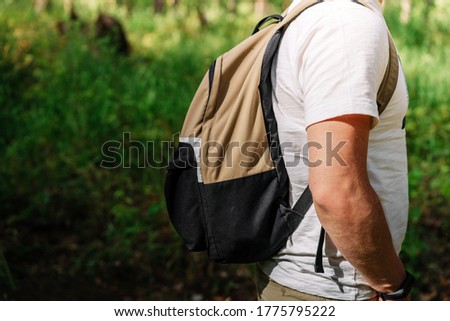 A young man with a backpack stands alone in a pine forest with a natural background, the concept of tourism and recreation, a place for text, copy space