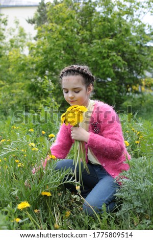 Spring portrait of a beautiful girl of eight years old with a beautiful braid hairstyle on nature in summer blooming flowers