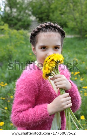 Spring portrait of a beautiful girl of eight years old with a beautiful braid hairstyle on nature in summer blooming flowers