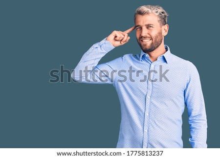 Young handsome blond man wearing elegant shirt smiling pointing to head with one finger, great idea or thought, good memory 