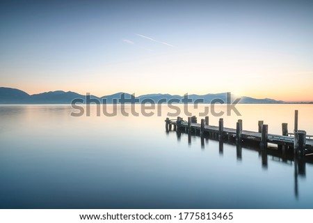 Wooden pier or jetty and lake at sunrise. Torre del Lago Puccini, Versilia, Massaciuccoli lake, Tuscany, Italy, Europe Royalty-Free Stock Photo #1775813465