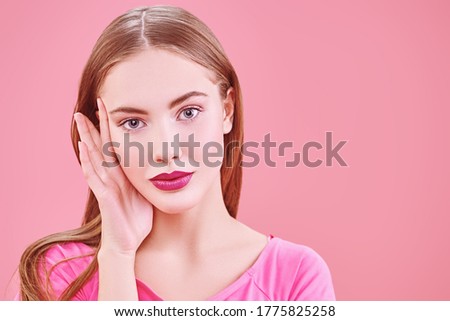 Cute girl teenager in a pink t-shirt posing on a pink background. Copy space. Youth style. Cosmetics and make-up.
