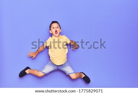 Adorable kid wearing casual clothes jumping over isolated purple background