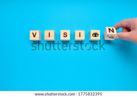 Man turning a die of the word VISION on a blue background. Medical concept