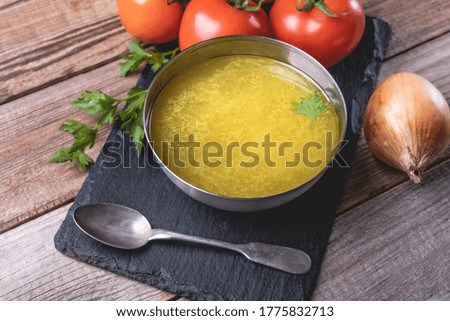 Chicken soup bouillon in a bowl on rustic wooden table