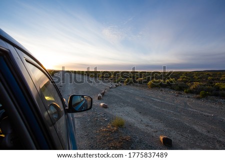 Wide angle view out the window of a bakkie/pick up truck on a lonely road in the Tankwa Karoo at sunrise