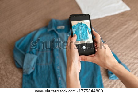 Woman taking photo of denim shirt on smartphone 