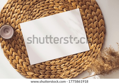 Blank card mock-up in neutral beige colors lying on straw mat