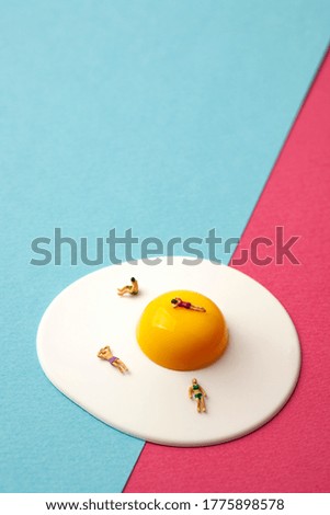 miniature people on egg with blue and pink background