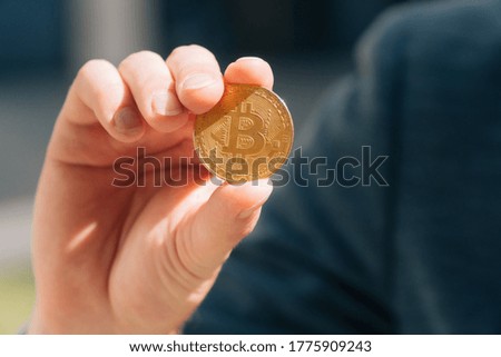Male European businessman holds in his hands bitcoin coins in the fresh air close-up. Virtual money in the online store