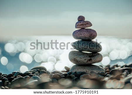 Balanced Pebbles Pyramid on the Beach on Sunny Day and Clear Sky at Sunset. Blue Sea on Background. Selective focus, Bokeh. Zen stones on sea beach, meditation, spa, harmony, calm, balance concept Royalty-Free Stock Photo #1775910191