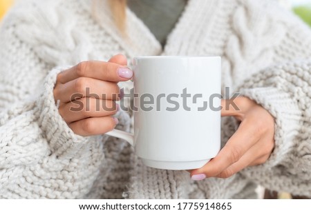 White ceramic mug mockup. Woman in Sweater Holding a Warm Cup of Coffee. Copy space for your print Royalty-Free Stock Photo #1775914865