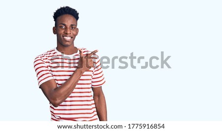 Young african american man wearing casual clothes cheerful with a smile of face pointing with hand and finger up to the side with happy and natural expression on face 