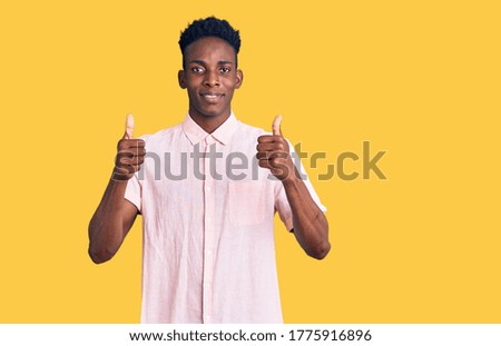 Young african american man wearing casual clothes success sign doing positive gesture with hand, thumbs up smiling and happy. cheerful expression and winner gesture. 