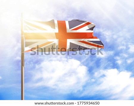 National flag of United Kingdom on a flagpole in front of blue sky