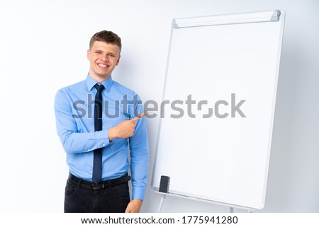Young businessman giving a presentation on white board pointing to the side to present a product