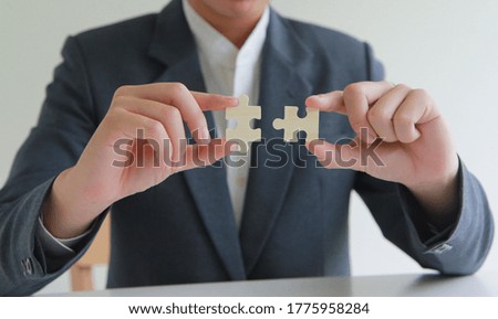 hand of a man connecting jigsaw puzzle with sunlight effect, Business solutions, success and strategy concept.