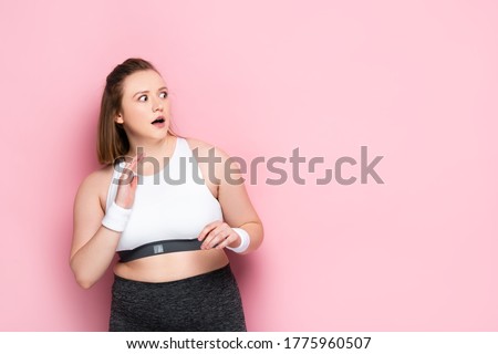 scared overweight girl gesturing while looking away on pink