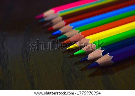 Row of different colored wood pencil crayon placed on top of an antique wooden desk