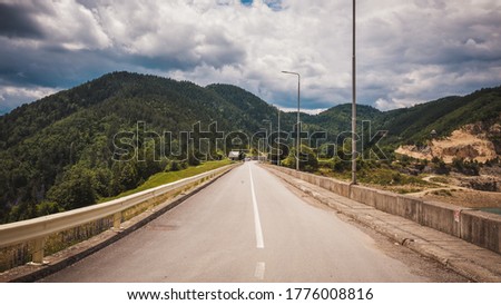 Road by the Zaovine lake with cloudy sky and mountains in the background