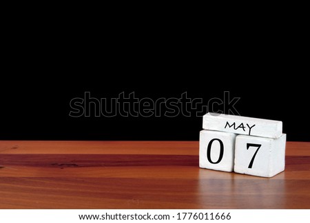 7 May calendar month. 7 days of the month. Reflected calendar on wooden floor with black background
