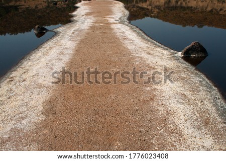 MINERAL ENCRUSTED RAISED PATHWAY INTO A SALT LAKE AT THE BOTTOM ON A METEOR LAKE