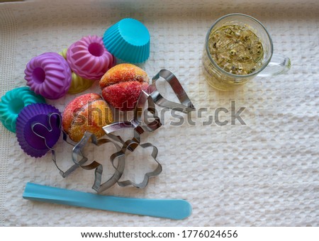 Children's cakes for the holidays, multi-colored, peaching form , baking dishes for cookies, a cup of tea with chamomile on white textile
